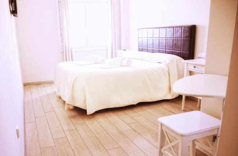 Habitación iluminada con la luz del sol con una cama de matrimonio
